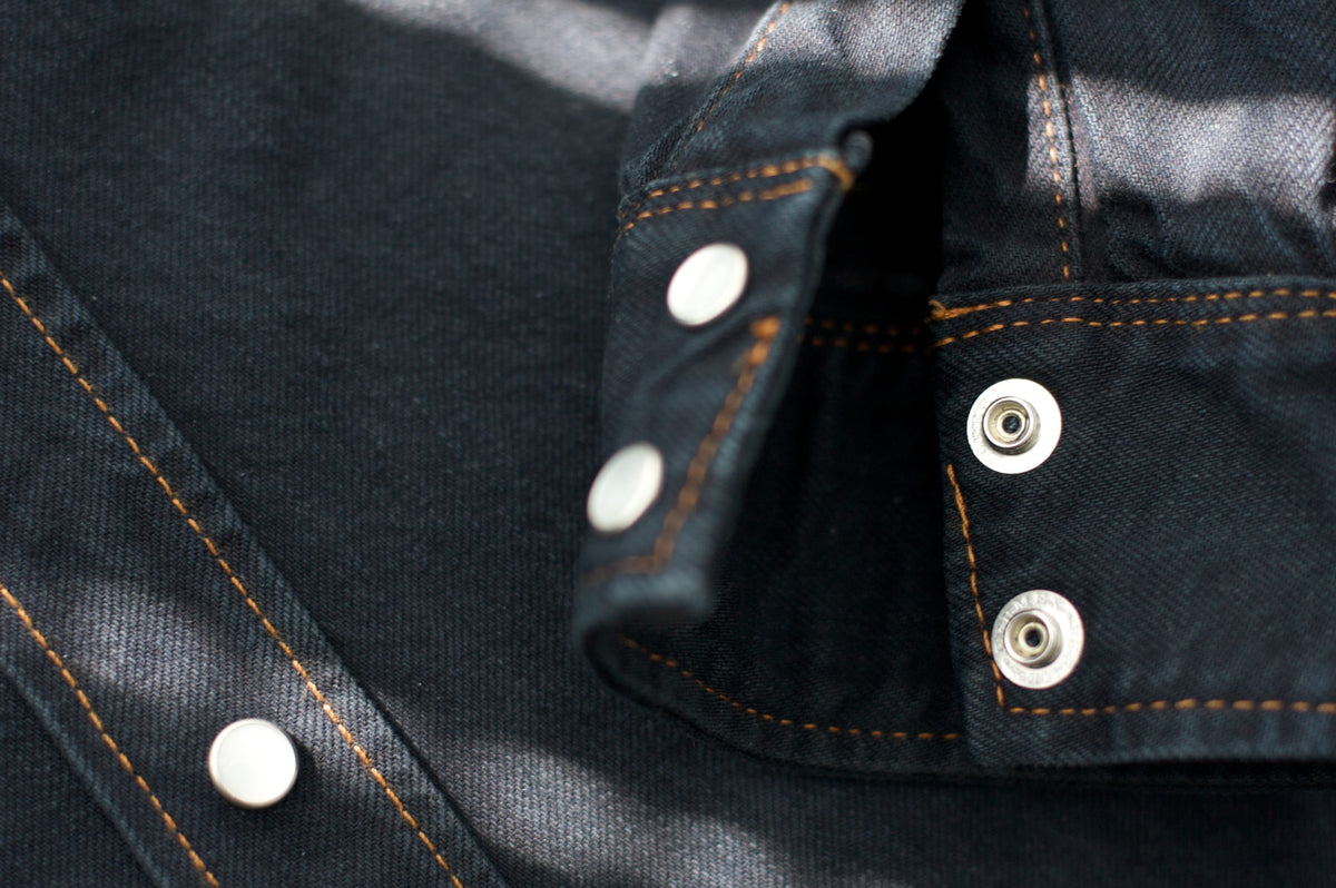 Detalle de botones y costuras de un jean Raindoor